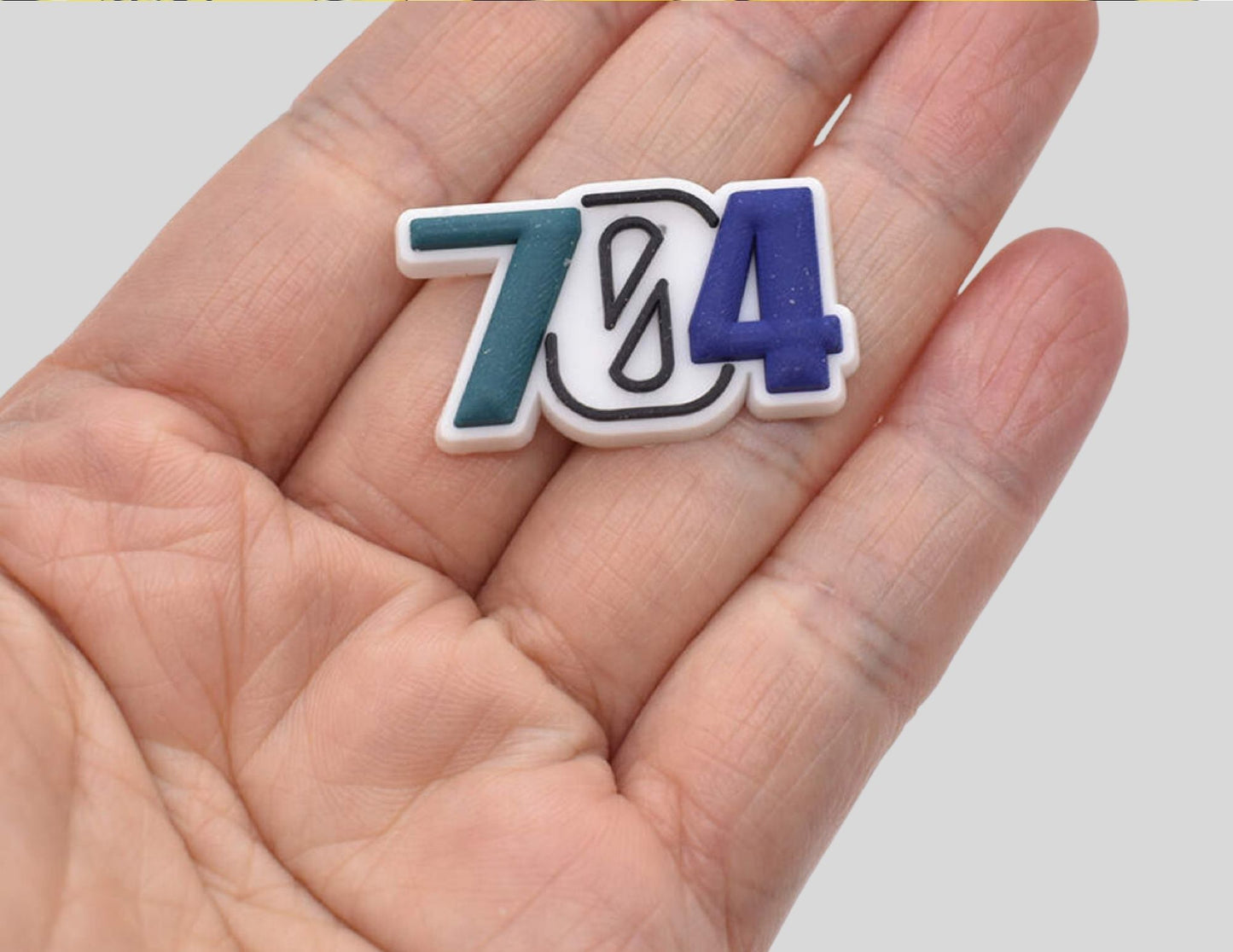 The size of the Malcontents 704 area code shows the charm fitting in the palm of a hand.