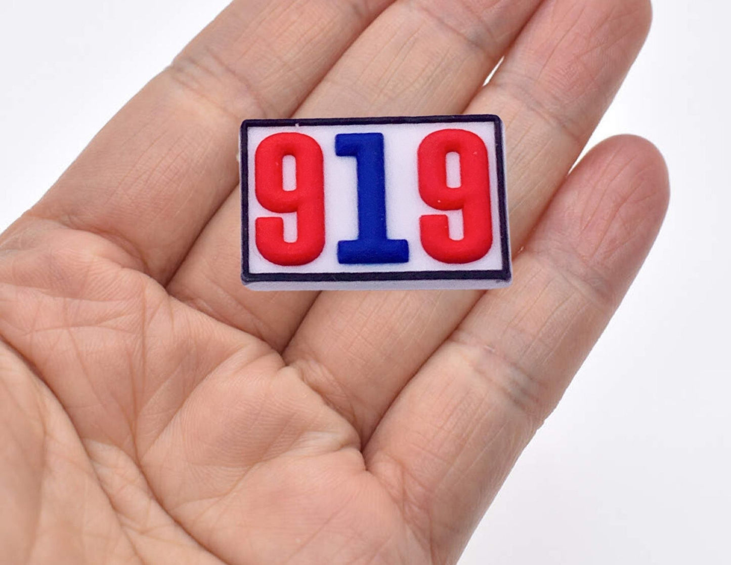 Malcontents Croc Jibbit shows 919 area code: red and blue numbers inside of a white box, in the palm of a hand.